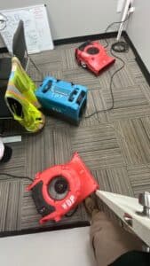 Commercial-grade air movers and dehumidifier equipment set up inside an office with carpet tiles for professional water damage drying and restoration by Water Damage Pros Nashville.