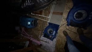 Water damage drying equipment running in a crawlspace to remove trapped moisture