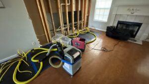 Water damage drying setup in a Nashville home with floor mats, hoses, and dehumidifier during leak cleanup