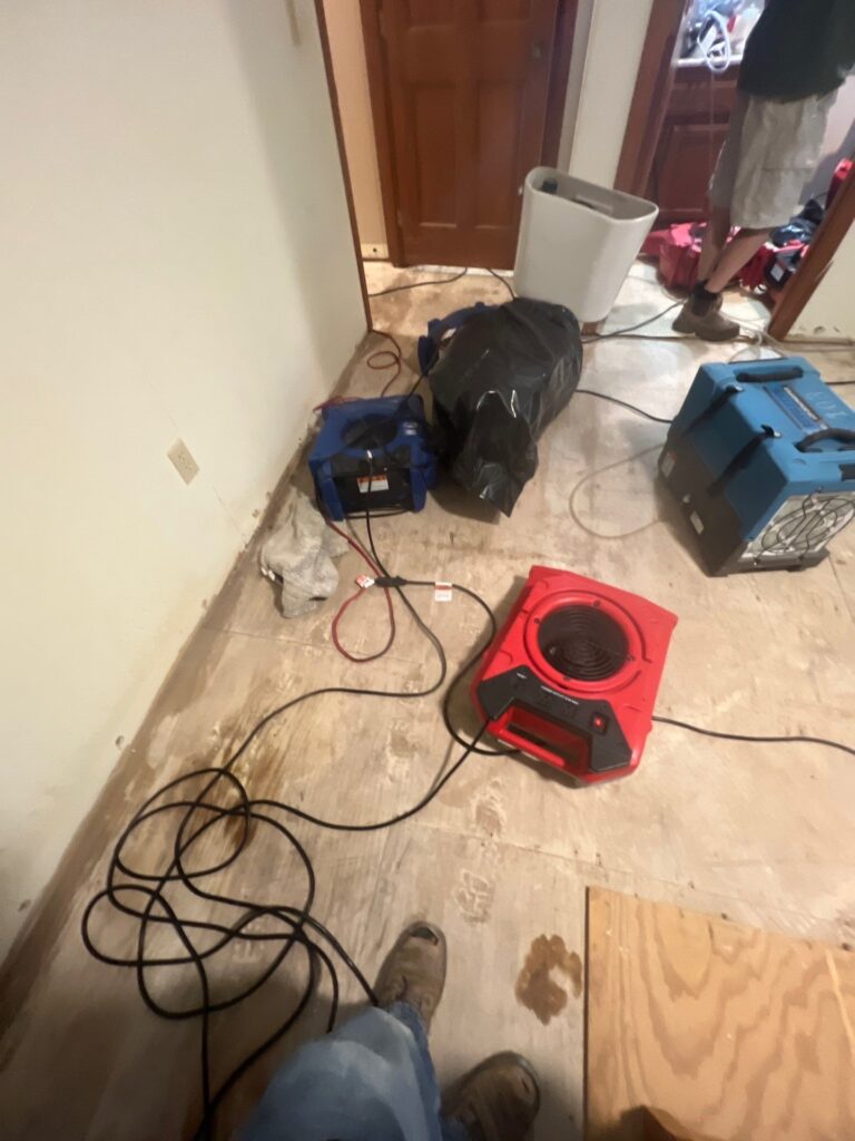Interior water damage drying equipment set up on exposed flooring with removed baseboards