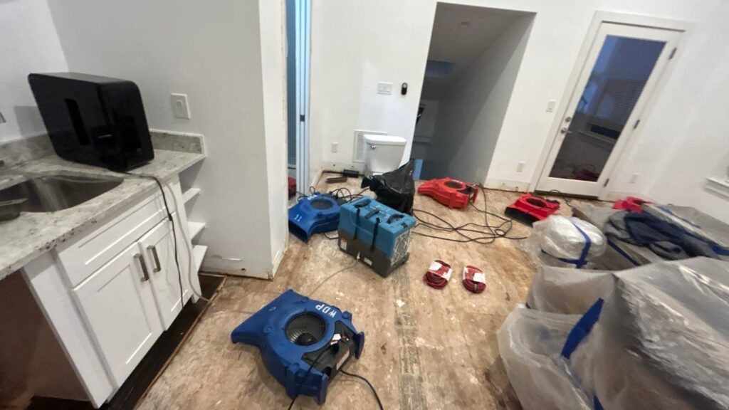 Water damage restoration drying equipment set up on exposed flooring after a leak
