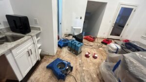 Water damage restoration drying equipment set up on exposed flooring after a leak